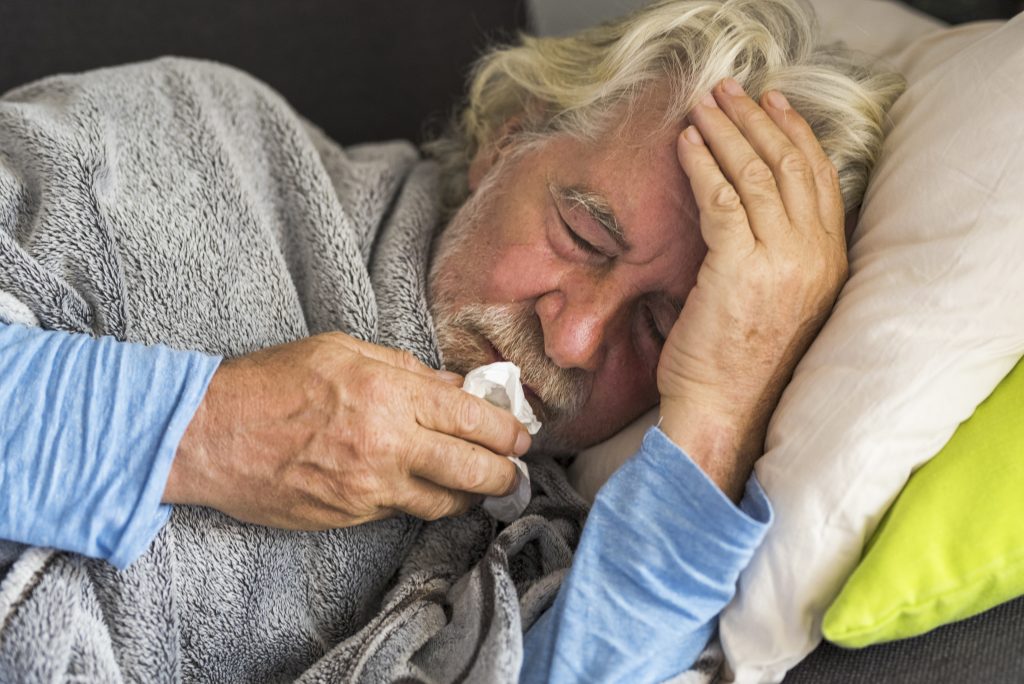 Senior mit Kopfschmerzen liegt im Bett